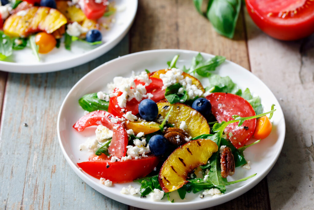 Salade estivale avec des légumes et des pêches dans une assiette sur une table