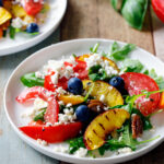 Zomerse salade met groenten en perziken op een bord op tafel.