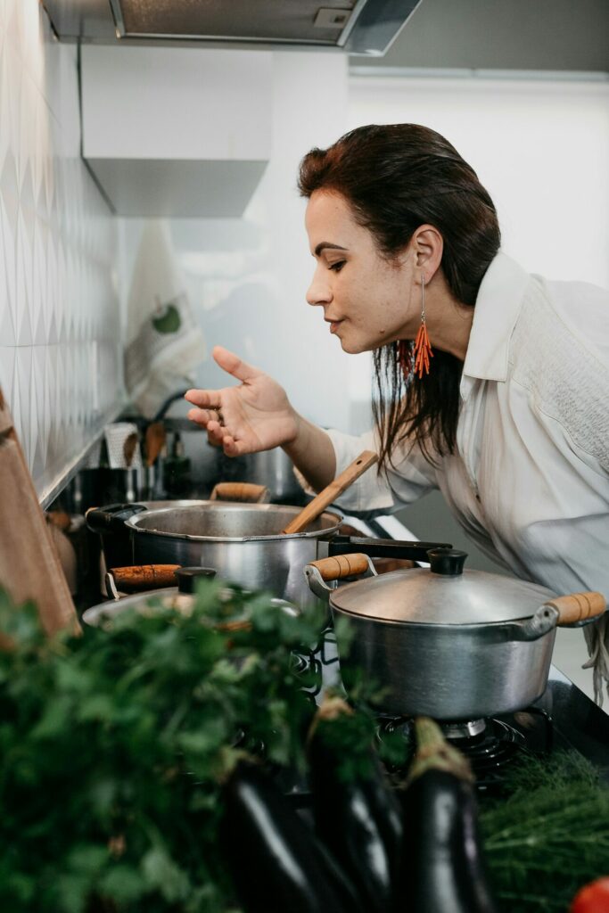 une femme qui sent les bons plats qui sont occupés de cuire sur le feu avec sa cuisine maison